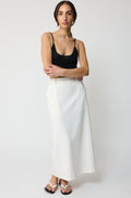 Woman wearing a black top and white skirt on a white background