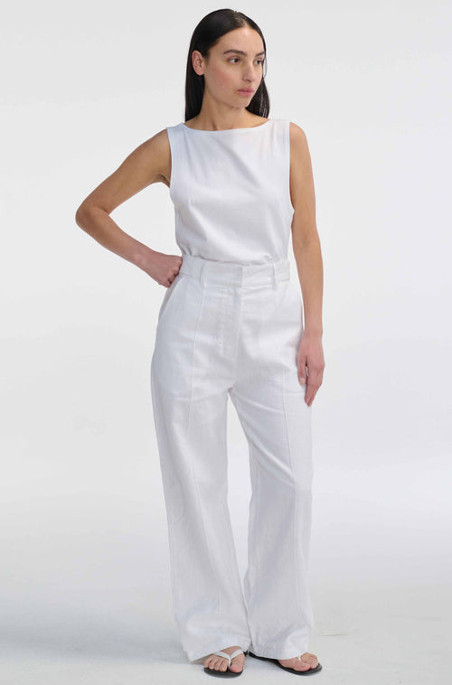 Woman wearing a white sleeveless top and wide-leg pants on a white background