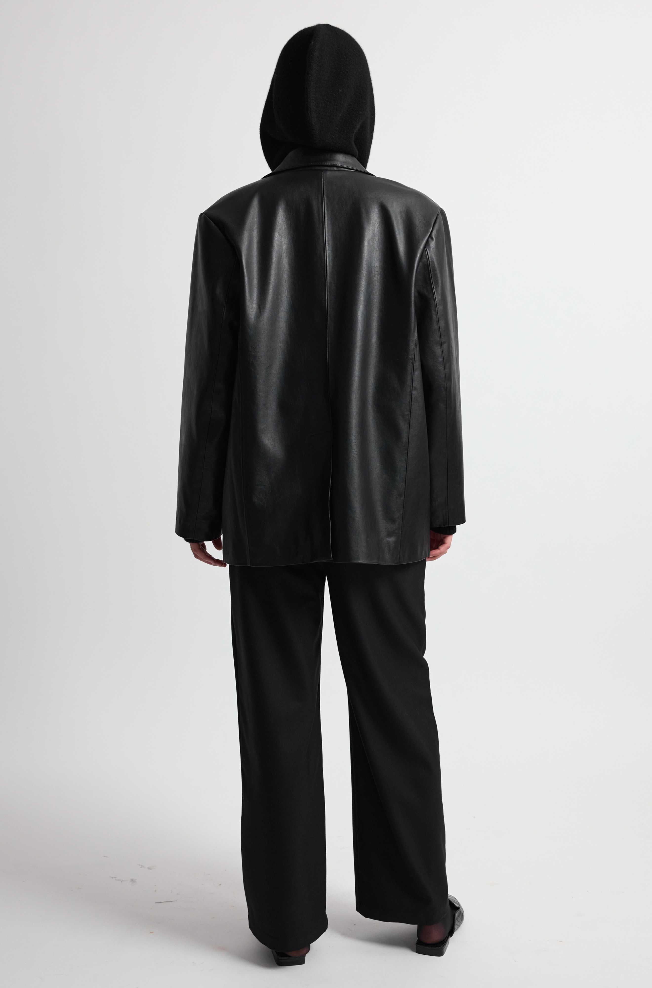 Person wearing a black leather jacket and pants on a white background