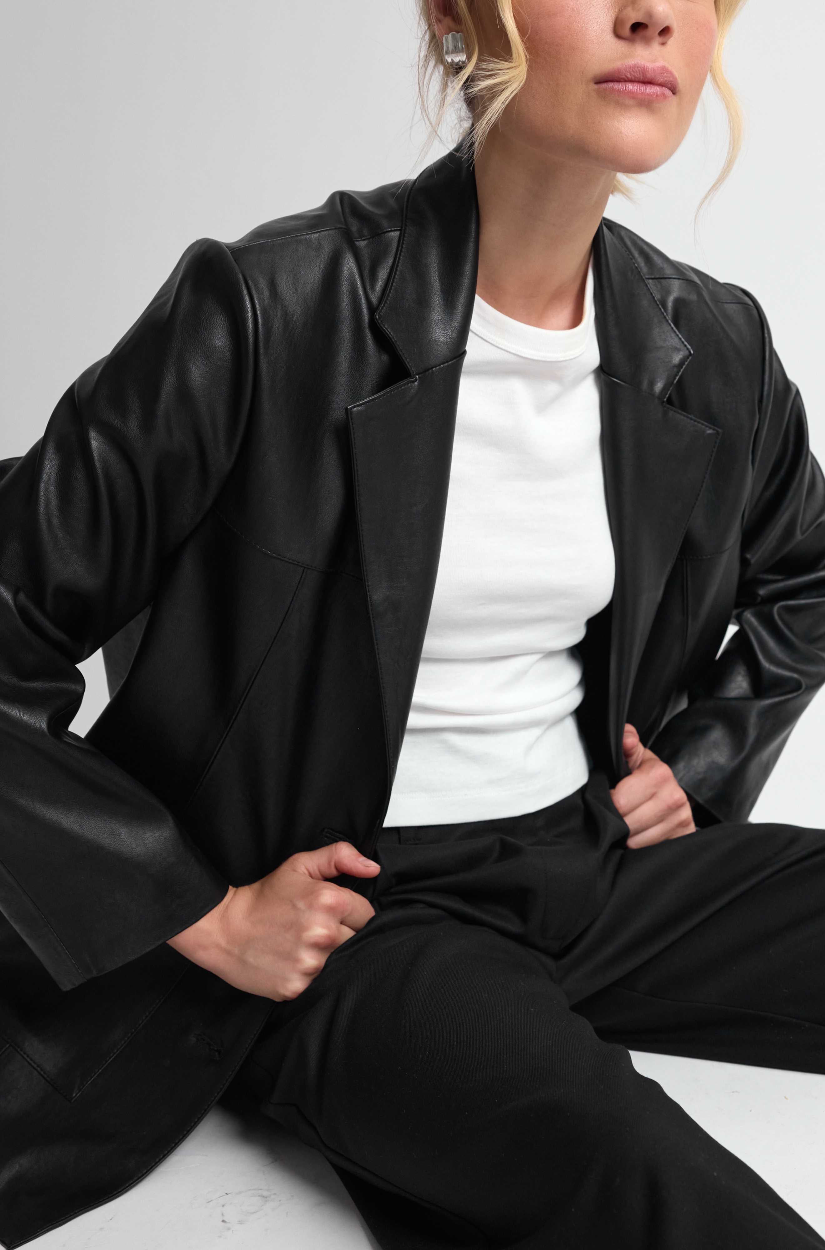 Person wearing a black leather jacket and white shirt on a white background