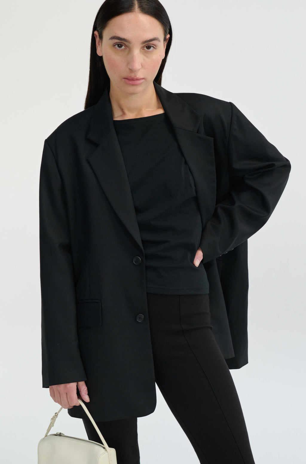 Woman wearing a black blazer and pants with a white background