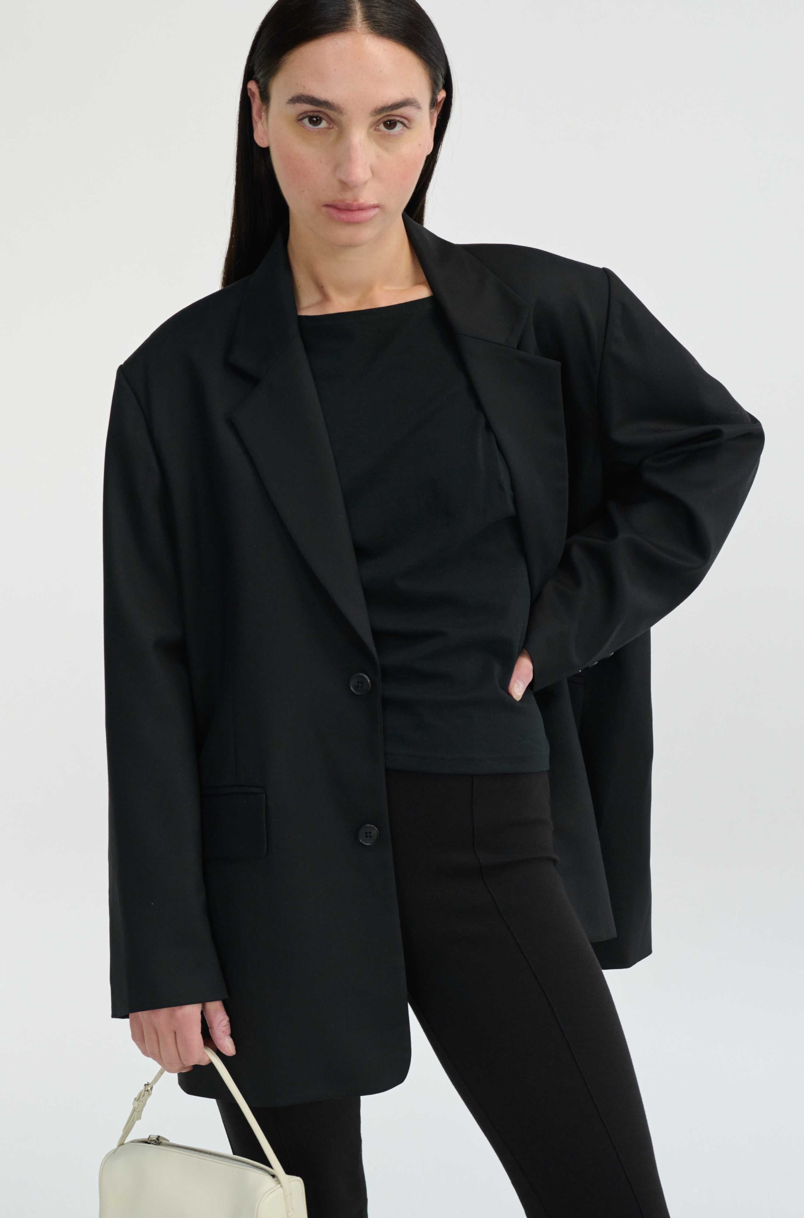 Woman wearing a black blazer and pants with a white background
