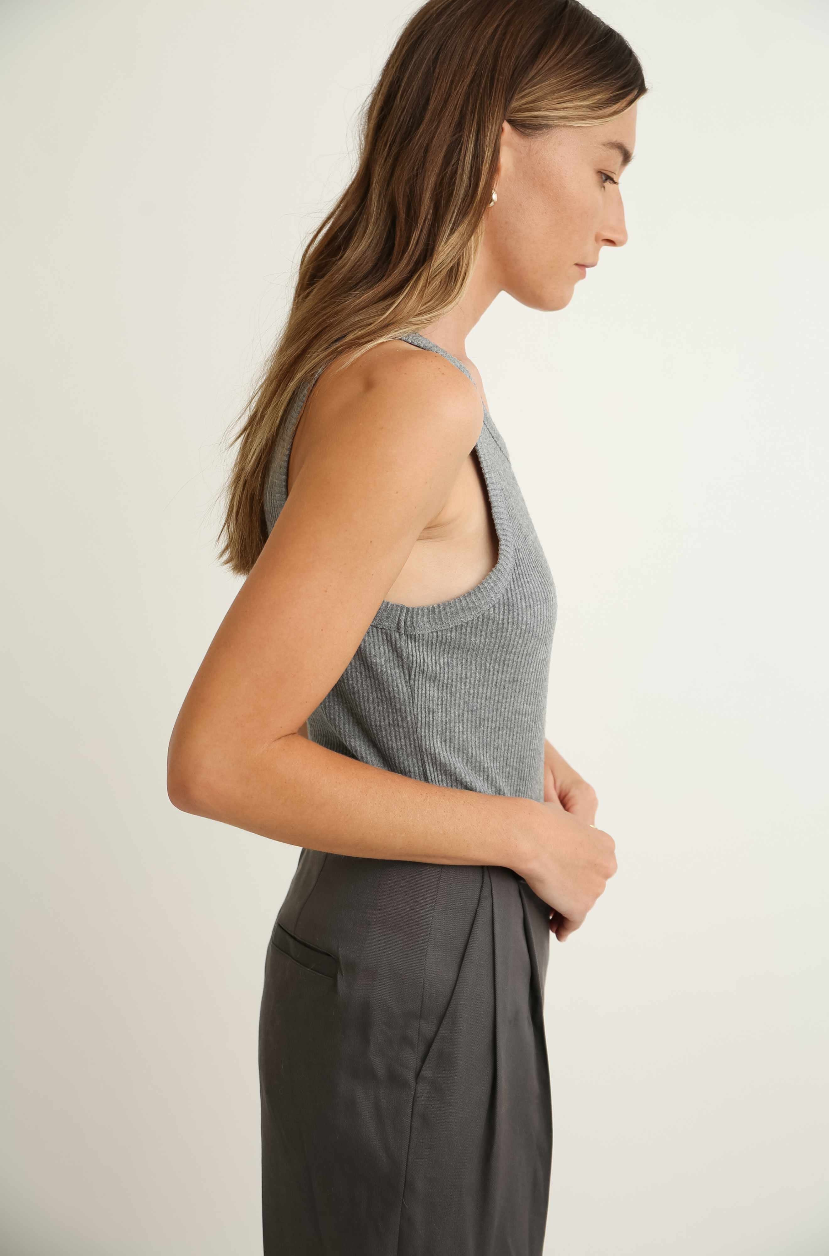 Woman wearing a gray sleeveless top and pants against a plain background