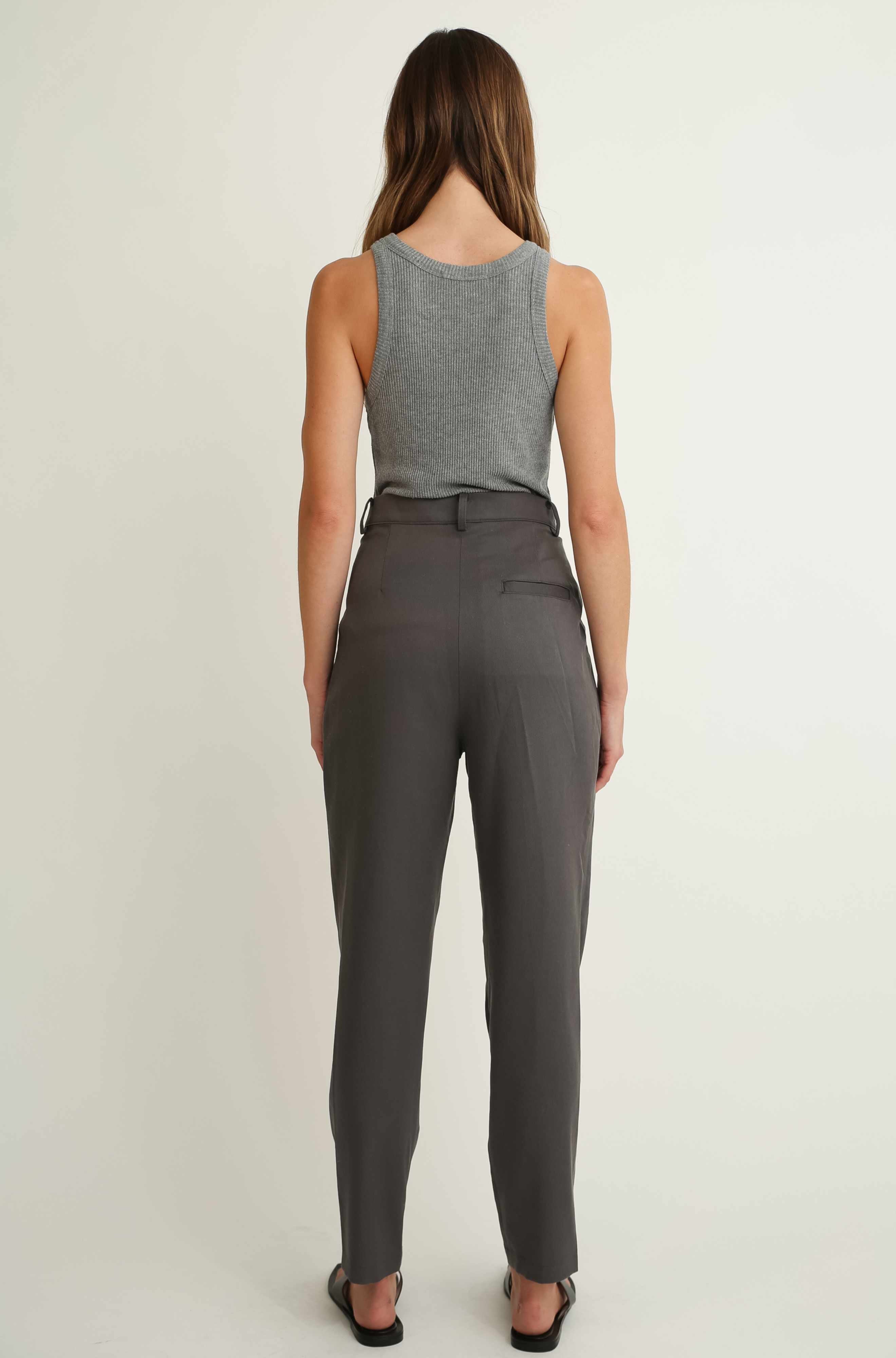 Woman wearing a gray sleeveless top and gray pants on a white background