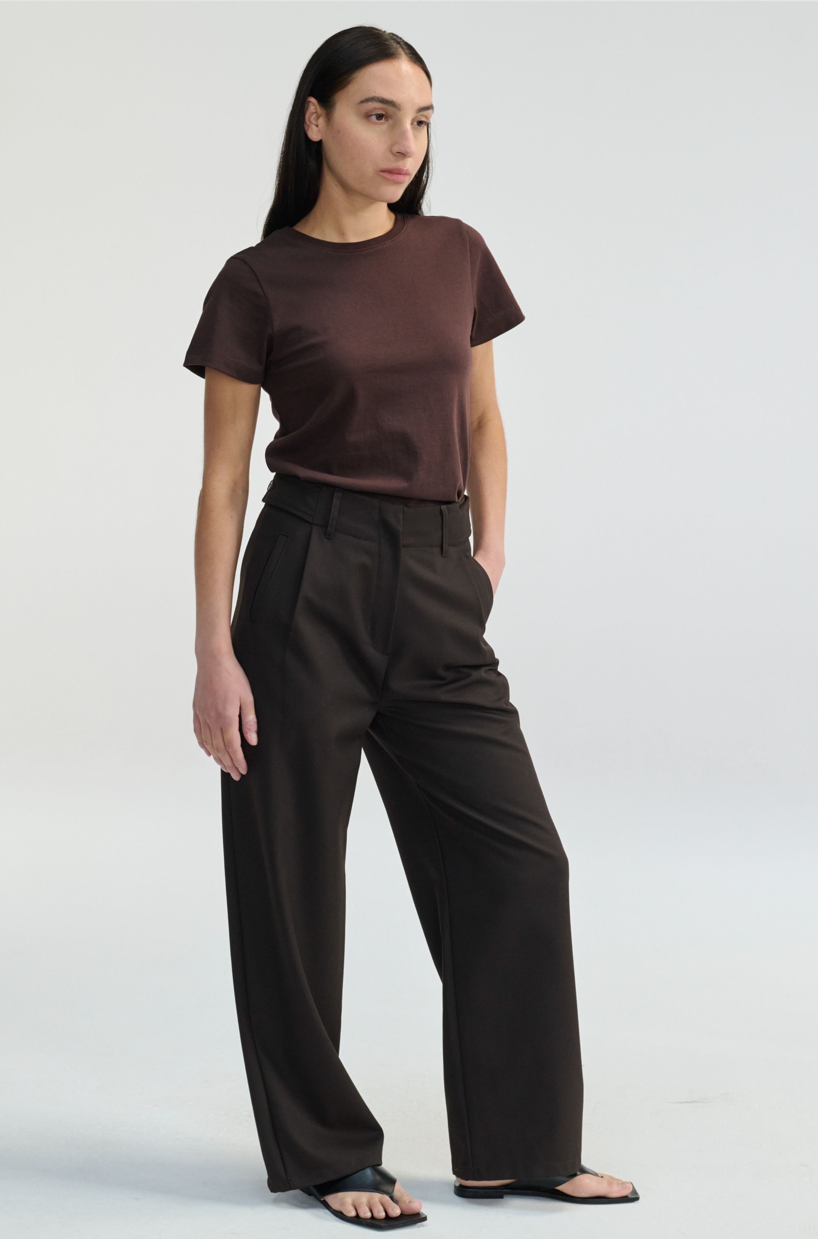 Woman wearing a brown t-shirt and brown pants on a white background
