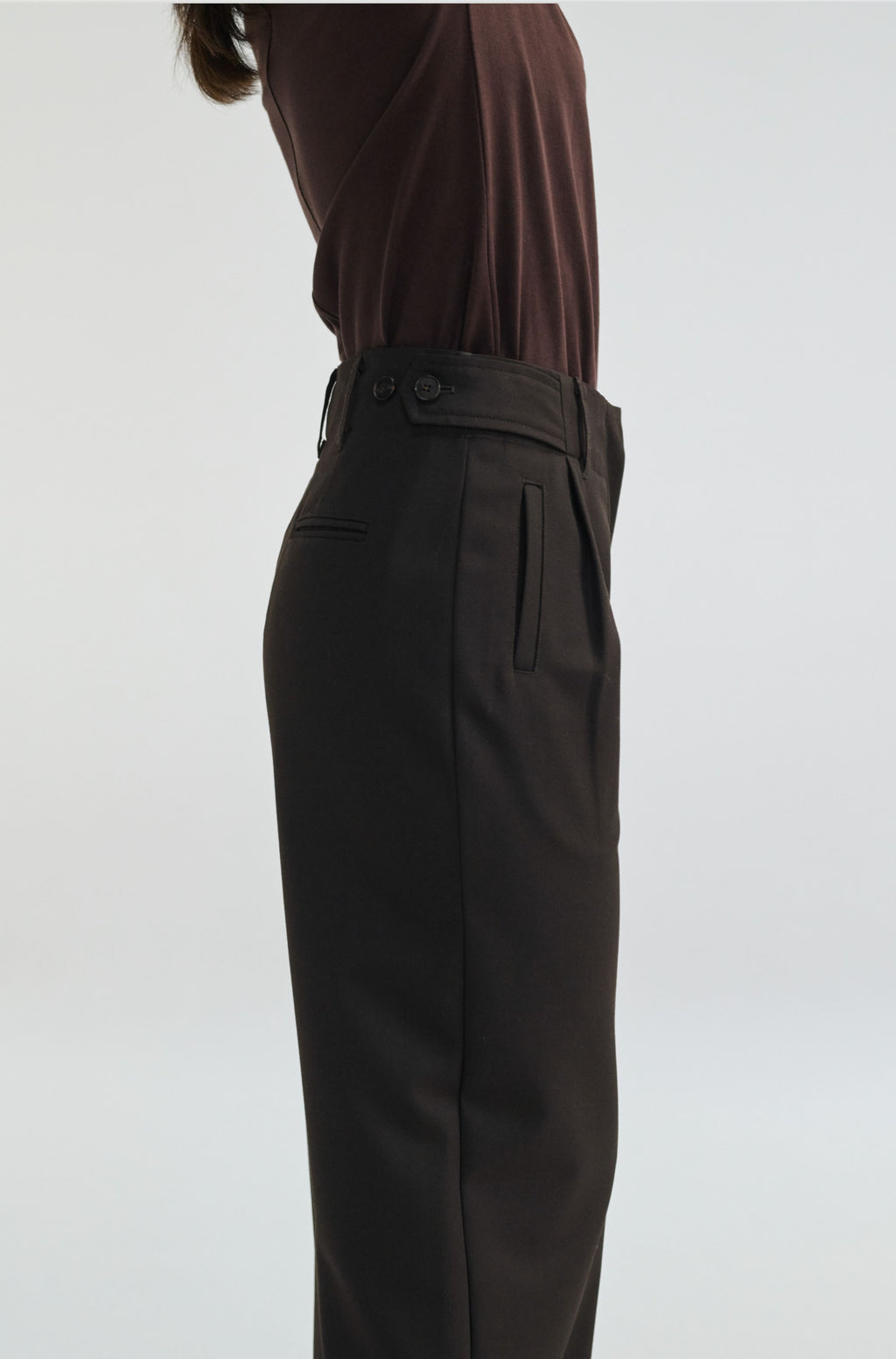 Dark brown pants worn by a person on a white background