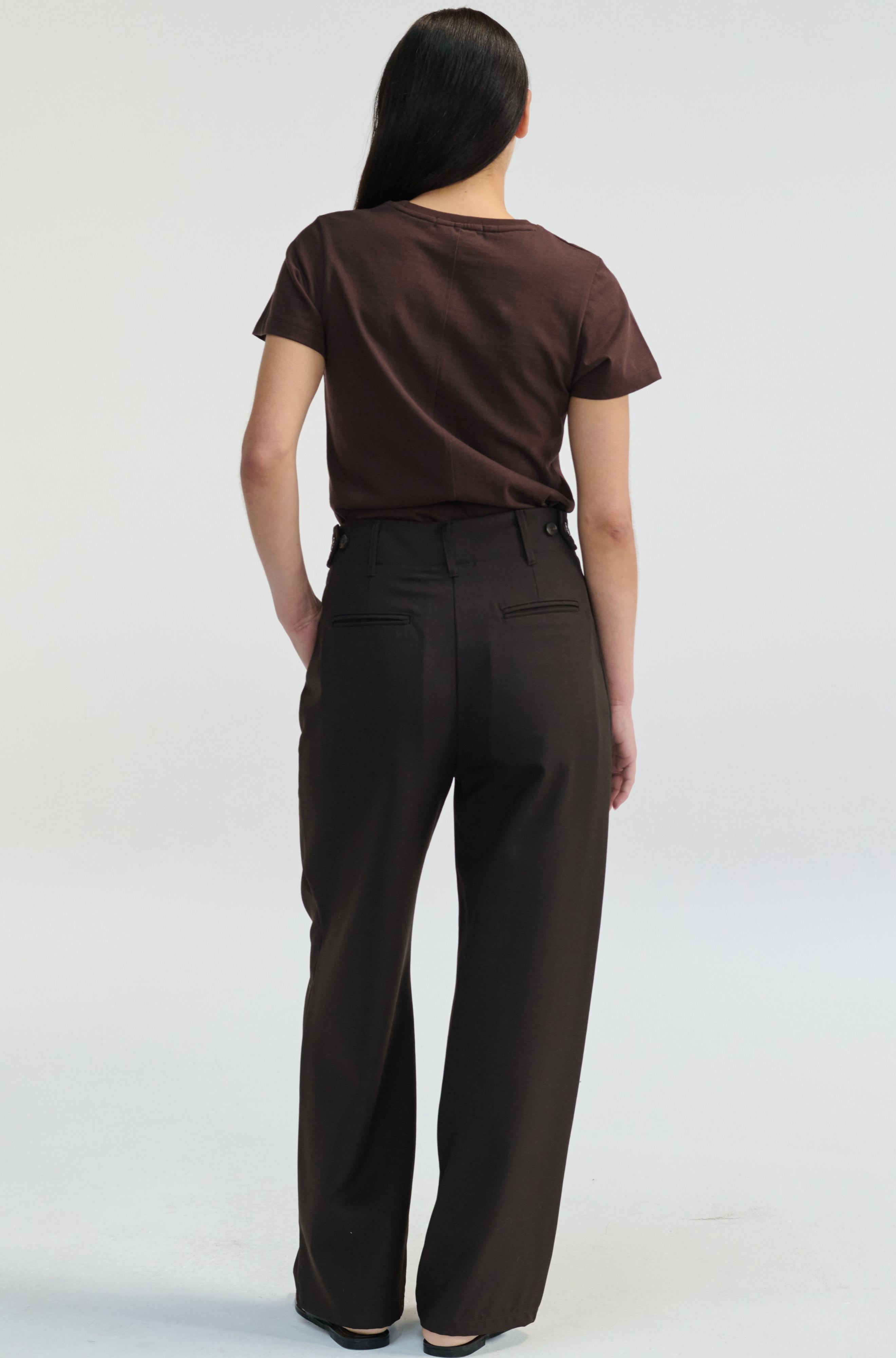 Person wearing a brown t-shirt and dark pants on a white background