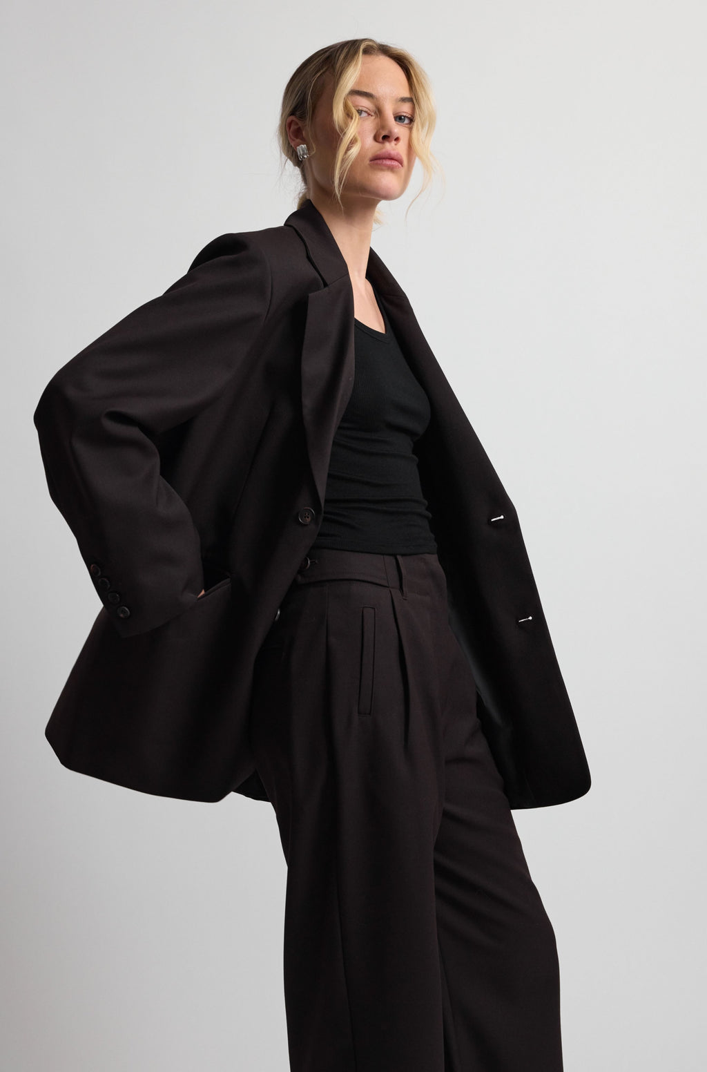 Person wearing a dark brown coat and pants on a plain background