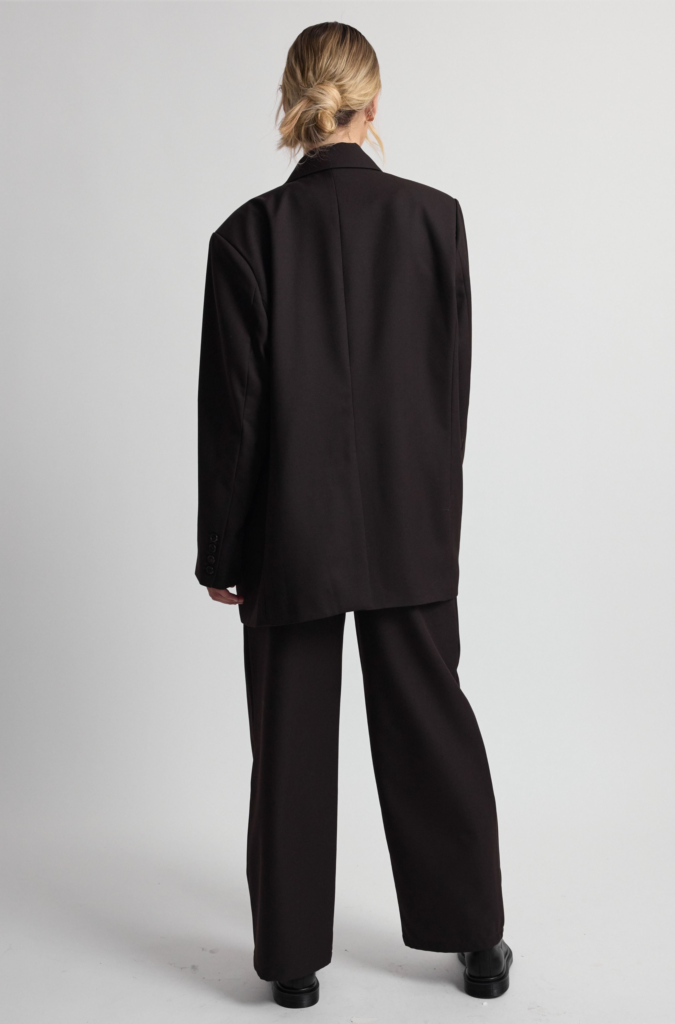 Person wearing a dark brown suit on a plain background